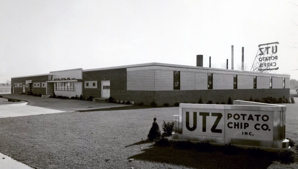 Black-and-white photo of a factory building with an Utz Potato Chip Co. sign out front.