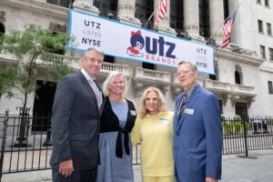 From left, Dylan Lissette, Stacie Lissette, Jane Rice and Mike Rice stand in front of an Utz Brands banner.