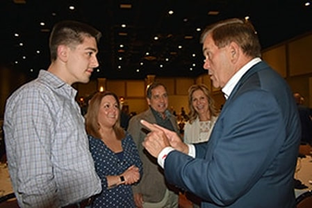 Former Gov. Tom Ridge, right, talks passionately with a young male student and his family.